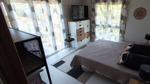 A bedroom with a bed, bedside tables, a TV, a small table with a plant, and a window with curtains. - 3-bedroom single-family home, 3 km from the beaches and close to everything: restaurants, movie theater, park, and sports facilities (La Garde)