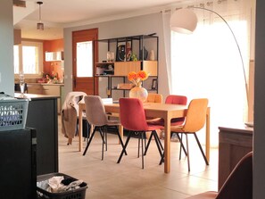 A dining area with a wooden table, chairs, and a vase with flowers. - 3-bedroom single-family home, 3 km from the beaches and close to everything: restaurants, movie theater, park, and sports facilities (La Garde)