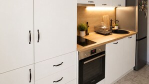 Eine moderne Küche mit weißen Schränken, einem schwarzen Backofen, einem Edelstahlkühlschrank und einer Holzarbeitsplatte.