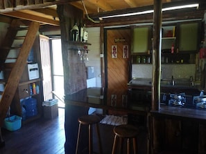 Ein rustikales Interieur mit einer Holztreppe, einer Bar mit Hockern und einem sichtbaren Schild für das Badezimmer.