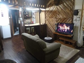 A living room with a sofa, a television, and a herringbone-patterned wall.