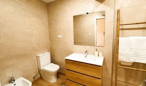 Ein kleines Badezimmer mit Toilette, Waschbecken, Spiegel und Handtuchhalter.