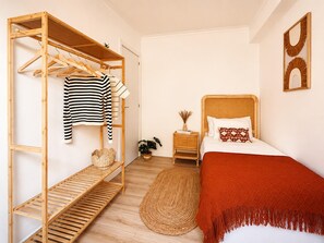 Ein Schlafzimmer mit einem Etagenbett, einem Nachttisch mit Lampe, einer Topfpflanze und einem Bett mit roter Decke.