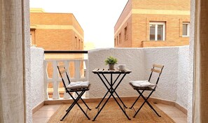 Ein Balkon mit zwei Stühlen, einem kleinen Tisch und einem Blumentopf.