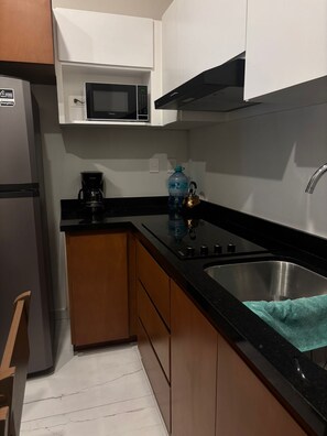 A kitchen with a refrigerator, microwave, stove, sink, and wooden cabinets. - Modern apartment in Torre Amberes | 2 blocks from the Malecon (Mazatlán)