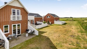 Tiilitalo, jossa on patio, katettu ulkotila oleskelua varten ja näkymä ympäröivälle maaseudulle.