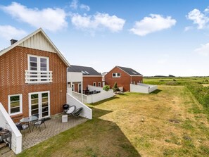 Ein Backsteinhaus mit Terrasse und überdachter Außenlounge, mit Blick auf die umliegende Landschaft.