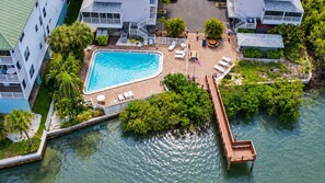 A pool area with a wooden deck, lounge chairs, and a flagpole. - Walk to Beach | Heated Pool w/ 6 beds (Indian Shores)