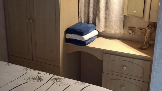 Quarto com cama, mesa de cabeceira com abajur, guarda-roupa e espelho.
