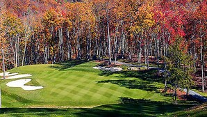 A golf course with a clear path, sand bunkers, and a backdrop of autumn-colored trees. - BLOCK Club Lodges at Trillium Presidential (Cashiers)