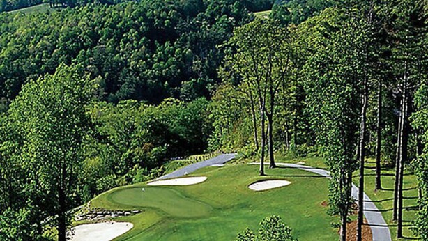A golf course with sand bunkers, a water body in the background, and a forested area. - BLOCK Club Lodges at Trillium Presidential (Cashiers)