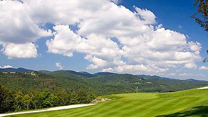 A golf course with a clear sky and distant mountains. - BLOCK Club Lodges at Trillium Presidential (Cashiers)