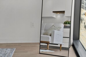 Ein modernes Wohnzimmer mit einem weißen Sofa, einem Spiegel der den Raum reflektiert und Blick auf die Straße.