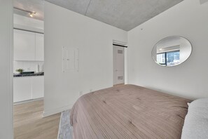 Une chambre à coucher avec un lit, un miroir rond et une vue sur la ville par la fenêtre.