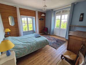 Una habitació amb llit, escriptori, cadira, finestra i porta.