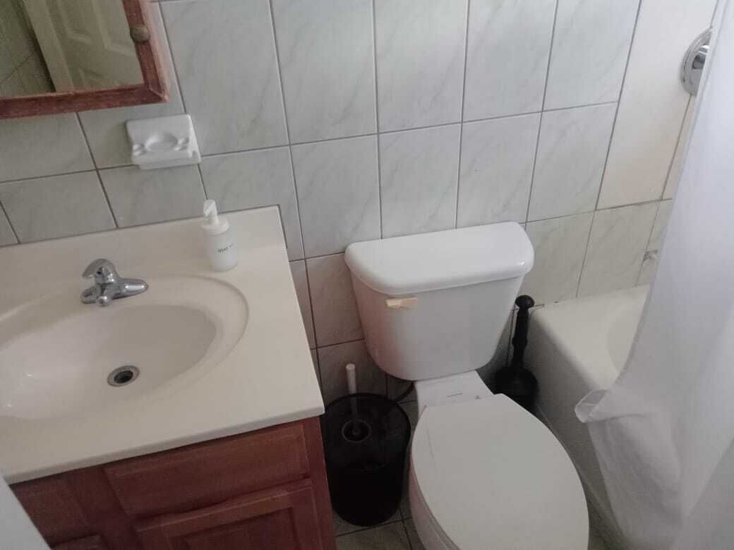 A bathroom with a white sink, toilet, and shower curtain.
