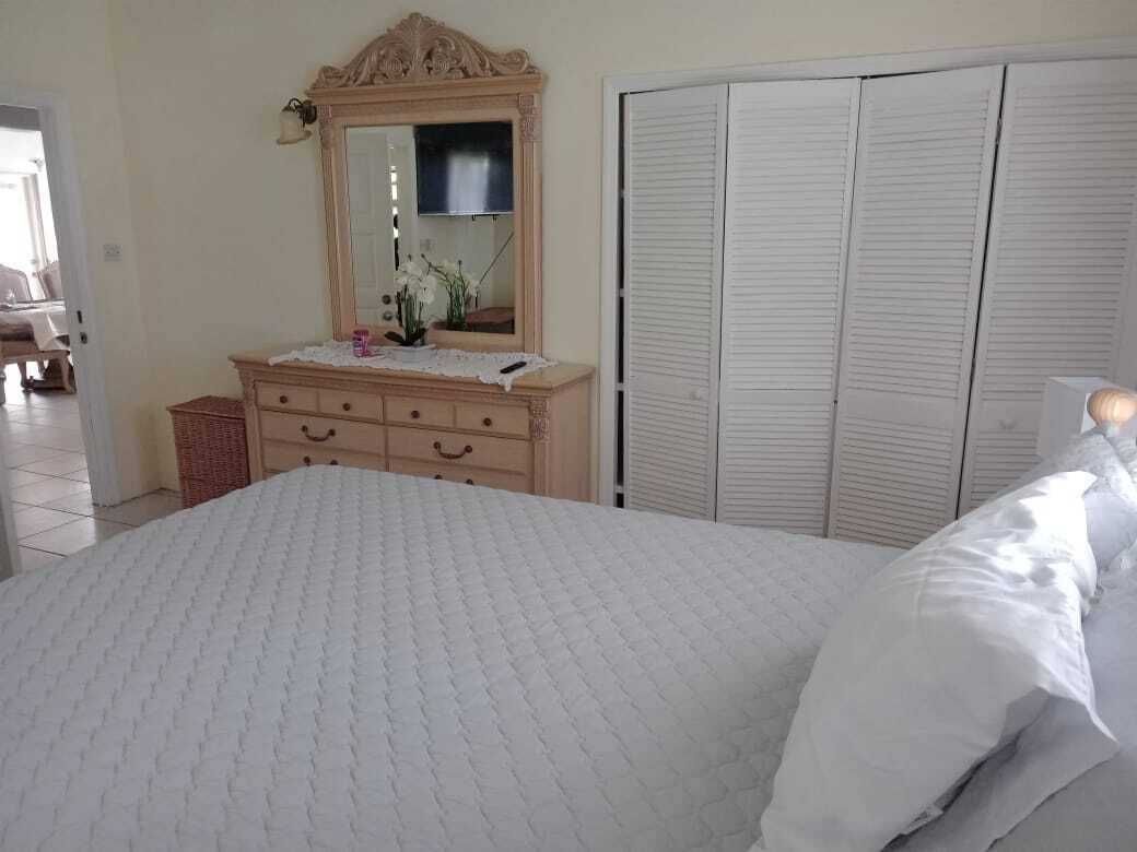 A bedroom with a bed, a dresser with a mirror, and a wardrobe.