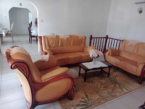 Un salon comprenant un canapé, un fauteuil et une table basse, ainsi qu’un tapis à motifs et une chaise en bois.