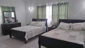 Une chambre avec deux lits, une commode, un miroir et une table de chevet avec une lampe.