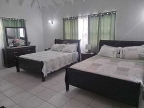 Une chambre avec deux lits, une commode, un miroir et une table de chevet avec une lampe.