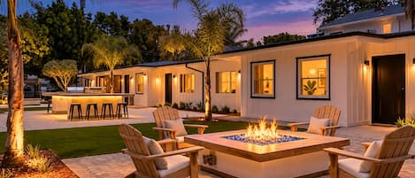 A modern outdoor patio with a fire feature, seating, and a bar area.
