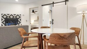 Una sala moderna con una mesa redonda, sillas de madera, un sofá y una chimenea.