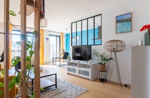 Ein modernes Wohnzimmer mit Fernseher, Holzmöbeln und Pflanzen.