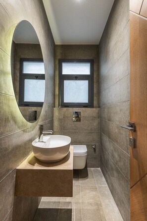 A modern bathroom with a large oval mirror, a freestanding sink, and two windows. - Spacious 3-bedroom apartment in fabulous Cairo with AC and gym (Cairo Governorate)
