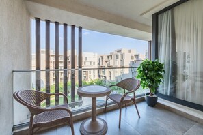 A balcony with wicker chairs, a small round table, and a potted plant. - Spacious 3-bedroom apartment in fabulous Cairo with AC and gym (Cairo Governorate)