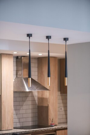 A modern kitchen with three pendant lights, a stainless steel range hood, and wooden cabinetry. - Spacious 3-bedroom apartment in fabulous Cairo with AC and gym (Cairo Governorate)