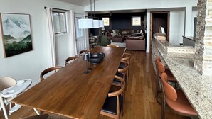 Un comedor amplio con una larga mesa de madera, sillas acolchadas y un moderno ventilador de techo.