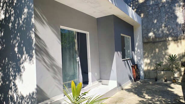 Un edificio moderno con techo plano, ventanas amplias y un patio de concreto con plantas en macetas.