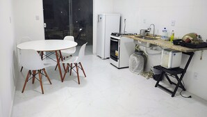 Una cocina compacta con una mesa y sillas, refrigerador, estufa y pileta.