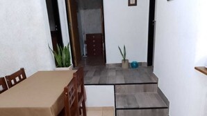 A dining area with a table and chairs, a potted plant, and a staircase leading to another room.