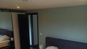 Et soveværelse med en stor seng, to puder, et sengebord med en lampe og et klædeskab.