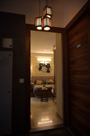 Ein Hotelzimmer mit Bett, Nachttisch und einer Holztür mit einer Nummer.