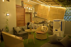 Ein gemütlicher Innenraum mit Korbmöbeln, einem kleinen Tisch und einem Deckenventilator.