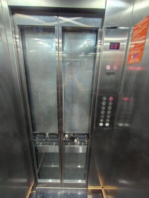 An elevator with a digital display, control panel, and safety instructions. - SkyNest stays- A private terrace garden | Near cyber hub  & galleria market |  (Gurugram)