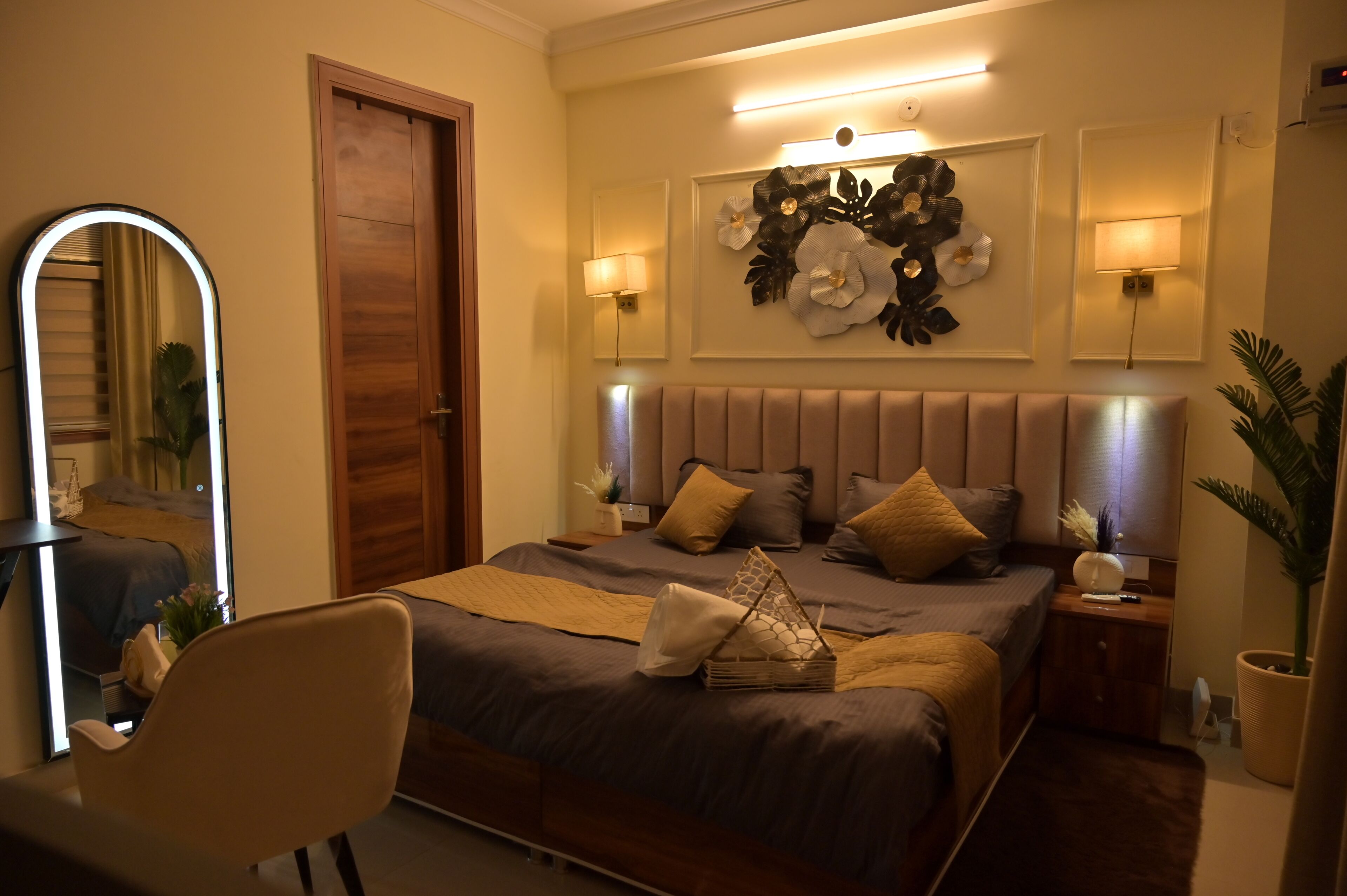 A bedroom with a large bed, bedside lamps, a mirror, and a wall-mounted light fixture.