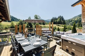 Un espace extérieur aménagé pour les repas, avec une table pour quatre personnes, un jacuzzi et une vue sur le paysage environnant.