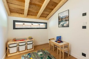 A room with a wooden ceiling, a window, a wall-mounted picture, a desk with chairs, and storage units. - Chalet des Granges • 12 Guests • Spa & Private Cinema (Morzine)