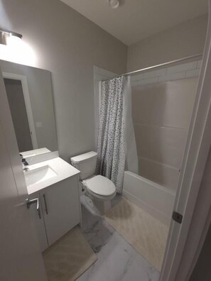 A bathroom with a toilet, sink, and shower area. - Spacious and Modern 2-bedroom Apartment in Calgary (Calgary)