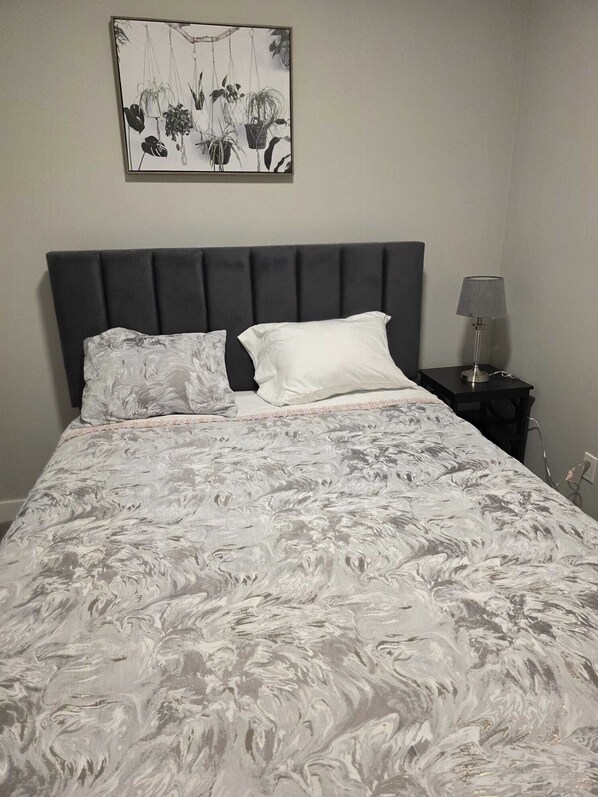 A bed with a grey headboard, white pillows, and a grey patterned bedspread. - Spacious and Modern 2-bedroom Apartment in Calgary (Calgary)