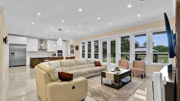 A modern living room with a sectional sofa, a coffee table, and a TV. - Luxury Mountain-View Estate on 1.8 Acres | Near Golden Ears Park & Hwy 1 (Maple Ridge)