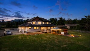 A two-story house with a covered patio, a driveway, and a lawn. - Luxury Mountain-View Estate on 1.8 Acres | Near Golden Ears Park & Hwy 1 (Maple Ridge)