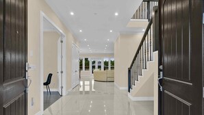 A spacious hallway with a staircase, a sofa, and a chair. - Luxury Mountain-View Estate on 1.8 Acres | Near Golden Ears Park & Hwy 1 (Maple Ridge)