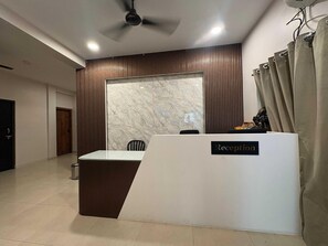 A reception desk with a marble wall, a ceiling fan, and a curtain. - Hotel O Aiims Bhubaneshwar (Bhubaneshwar)