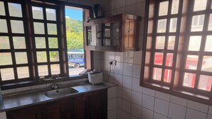 Una cocina con ventana, un fregadero, armarios y un microondas.