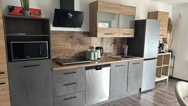 Una cucina moderna con forno a microonde, lavastoviglie e macchina del caffè integrati sul piano di lavoro.