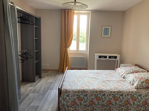 Una camera da letto con un letto, un armadio, un comodino e una finestra con tende.